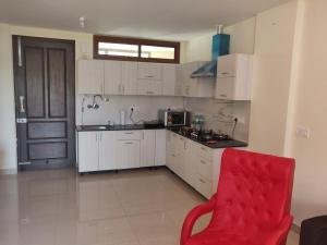 索兰2BHK Furnished Apartment/Near Kasauli/Barog/Luv Fun & Adventure的厨房配有白色橱柜和红色椅子