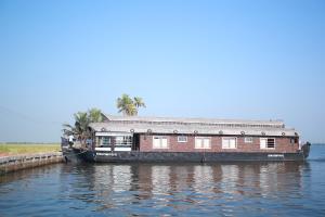 库玛拉孔Sreekrishna Houseboat - VACCINATED STAFF的船屋停靠在水面上