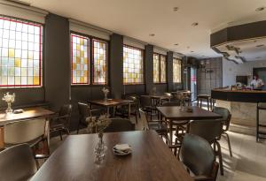 阿维拉唐卡梅洛酒店的餐厅设有木桌、椅子和窗户。