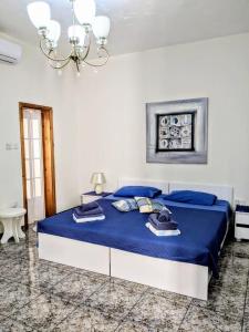 马尔萨斯卡拉Silia's Maisonette的一间卧室配有一张带蓝色床单和吊灯的床。