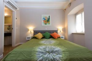杜布罗夫尼克弗洛雷斯别墅客房酒店的一间卧室配有带色彩缤纷的枕头的绿色床