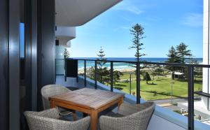 黄金海岸X Kirra Apartments的阳台配有桌椅,享有海景。