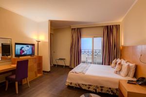 艾因苏赫纳Porto El Jabal Hotel的酒店客房配有一张床、一张书桌和一台电视。