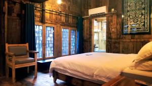 三江三江南夷民宿的一间卧室配有一张床、一把椅子和窗户。
