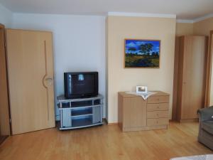 施特罗布尔Appartements Edda的客厅设有1个位于橱柜和1扇门上的电视