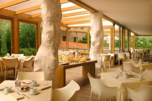 罗马贝斯特韦斯特亚比塔特酒店的餐厅设有白色的桌椅和窗户。