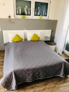 凯撒斯劳滕Apartment Oase- Kaiserslautern的一间卧室配有一张大床和两张黄色枕头