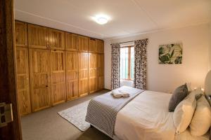格拉夫-里内特Garden Cottage的一间卧室配有一张带木制橱柜的床和窗户。