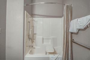 亨博尔Motel 6 Humble, TX - Houston International Airport的带淋浴和白色浴缸的浴室