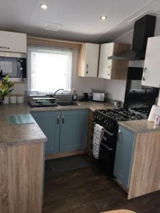 韦茅斯6 Swan View Haven, Littlesea的厨房配有蓝色橱柜和炉灶烤箱。