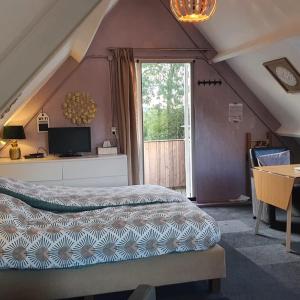 Broek op LangedijkLogeren op Dijk43的一间卧室配有一张床、一张桌子和一个窗户。