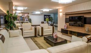 若昂佩索阿拉古纳普拉亚酒店的客厅配有白色家具和平面电视