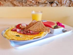 法鲁阳光之家酒店的早餐盘,包括煎蛋、烤面包和一杯果汁