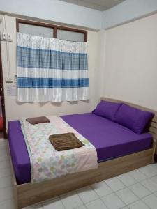 Ban Bang KhanNatcha Place TU Rangsit的一间卧室配有一张带紫色床单的床和窗户。