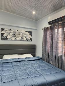 Trincity Preferred Place的一间卧室配有蓝色的床和花卉图案