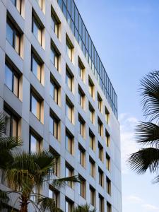 尼斯OKKO Hotels Nice Aéroport的一座高大的建筑,前面有棕榈树