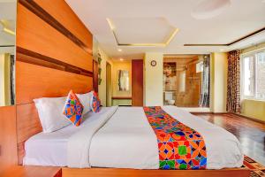 科代卡纳尔FabHotel Abirami Grand Inn的一间卧室配有一张大床和木制床头板