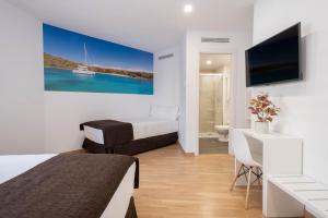 赫罗纳Hotel BESTPRICE Girona的酒店客房设有两张床、一张桌子和一台电视。