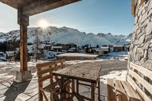 阿罗萨Alpslodge - Amelia的阳台上配有一张木桌和长凳,阳台上有积雪覆盖的山脉