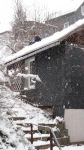 PiesauGasthaus Piesau - Thüringer Wald - Rennsteig的坐在房子屋顶上雪的人