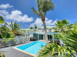 东方湾Villa Zandoli, walkable Orient Bay beach, private pool的一座带游泳池和棕榈树的房子