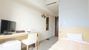 宇都宫UNIZO INN Express Utsunomiya的一间卧室配有一张床和一张书桌及电视