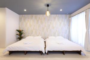 藤泽AQA ART 江の島的卧室设有2张床和白色的墙壁。