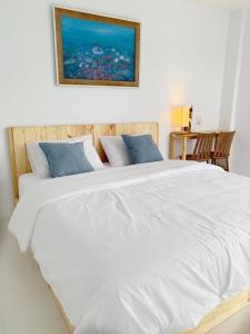 纳仲天Bannsukta的一张配有白色床单和蓝色枕头的大床