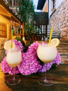 SirviellaPosada El Pareón的坐在桌子上,一边用鲜花一边喝杯装的两杯鸡尾酒