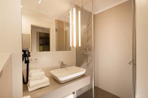 莱比锡th Hotel Leipzig Messe的白色的浴室设有水槽和淋浴。