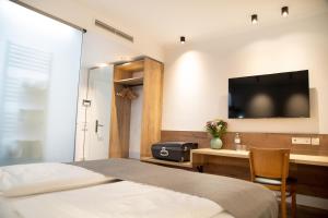 萨尔茨堡Hotel Restaurant Auerhahn的一间卧室配有一张床和一张书桌及电视