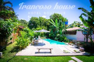 托兰克索Trancoso House - Hotel Boutique的一个带野餐桌和遮阳伞的度假游泳池