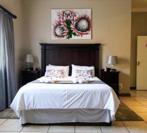 萨比Waterval Self-Catering Holiday Home的卧室配有一张带白色床单和鲜花的大床