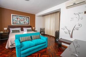 皮乌拉Posada Blanca Hotel Boutique的一间卧室配有一张床和一张蓝色的沙发