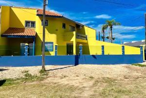 巴拉那州蓬塔尔Refúgio aconchegante com vista para o mar!的前面有蓝色栅栏的黄色房子