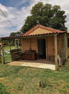 圣托梅-达斯莱特拉斯Chalés e Camping Taquaral的田野上带门廊的小房子