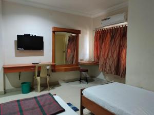 杜蒂戈林Hotel Geetha International的一间卧室配有一张床、一张书桌和一台电视