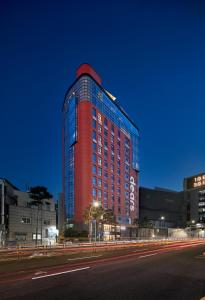 首尔Dears Myeongdong的一座高大的红色建筑,旁边灯火通明