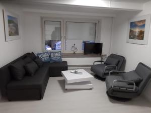 海德Ferienhaus Heide Zentrum的客厅配有黑色沙发和两把椅子