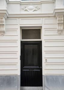 根特Chantilly Townhouse的白色建筑一侧的黑色门