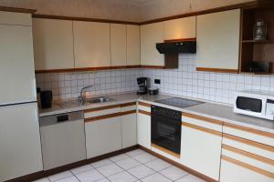 LützkampenFerienhaus Helten的厨房配有白色橱柜、水槽和微波炉