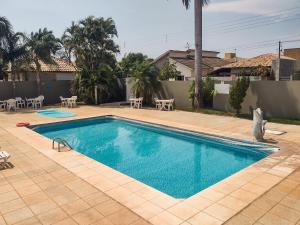 博尼图CLH Suites Bonito Sul的庭院内的游泳池,配有桌椅