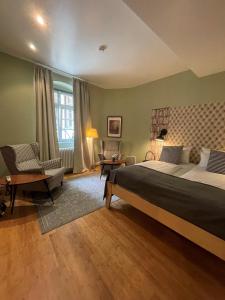 海德堡阿尔滕布吕克酒店的一间大卧室,配有一张大床和一把椅子
