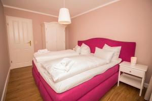 卡格斯多夫FerienDüne 4的客房内的粉红色床铺和白色床单