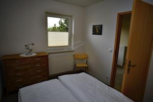 马尔洛Ferienhaus am Vogelpark - Trebelhaus Gesine的一间卧室配有一张床、一个梳妆台和一扇窗户。