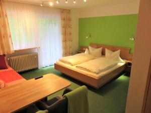 福森Ferienhaus Weiß, Sandra Weiß的绿色卧室配有床和桌子