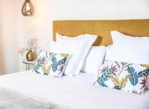 LiañoHotel Peñas Blancas的一间卧室配有带白色床单和热带枕头的床。