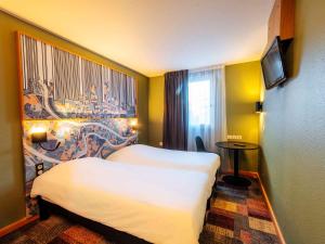 里昂Ibis Styles Lyon Croix Rousse的一间酒店客房,设有两张床和电视