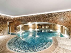 华沙莱佛士欧罗佩斯基华沙酒店的一座带瓷砖墙的建筑中的大型游泳池