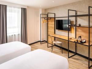 萨顿ibis London Sutton Point的酒店客房配有两张床和一张书桌